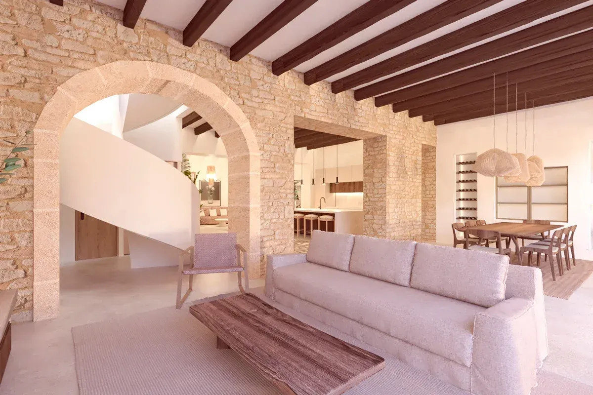 Salón de Son Morlà con arco de piedra, vigas vistas y escalera de caracol